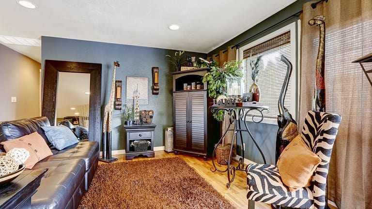 Beautiful tropical theme interior with exotic animal statues, brown soft rug, leather couch and zebra print chair