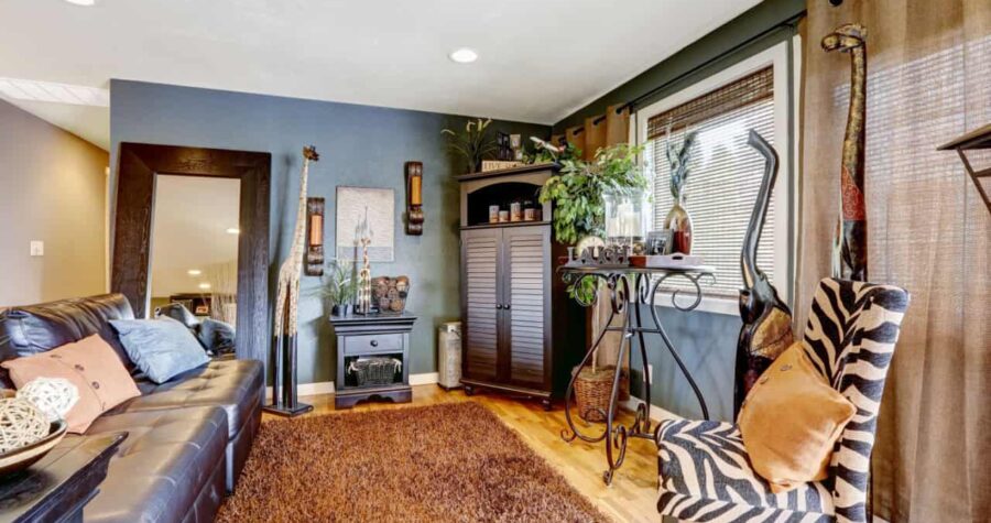 Beautiful tropical theme interior with exotic animal statues, brown soft rug, leather couch and zebra print chair