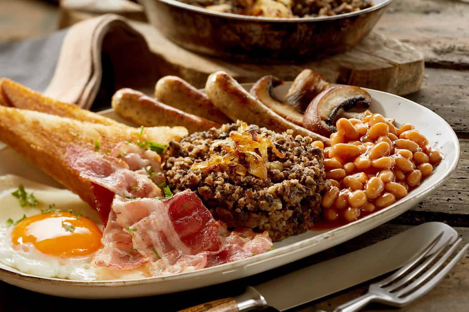 Breakfast plate with sausages, bacon, beans, fried eggs, and toast, hearty meal, close-up of food, savory breakfast, breakfast items arranged neatly on a plate, delicious and filling