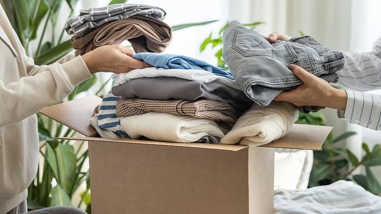 Women volunteers puts clothes in a donation box for charity or recycling.