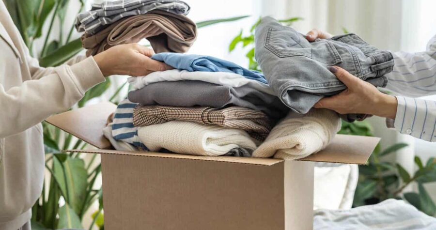 Women volunteers puts clothes in a donation box for charity or recycling.