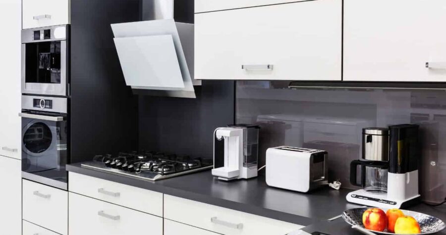 A residential kitchen, colored white and black, with sleek modern appliances and minimal clutter.