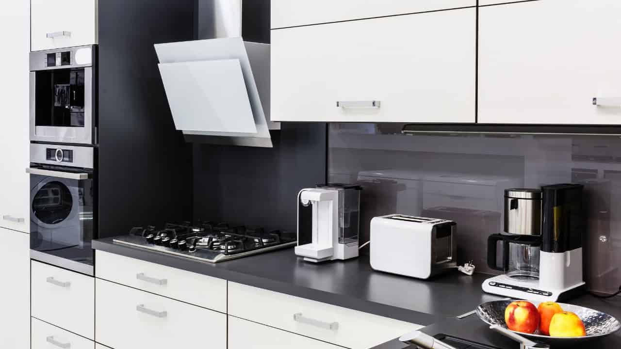 A residential kitchen, colored white and black, with sleek modern appliances and minimal clutter.