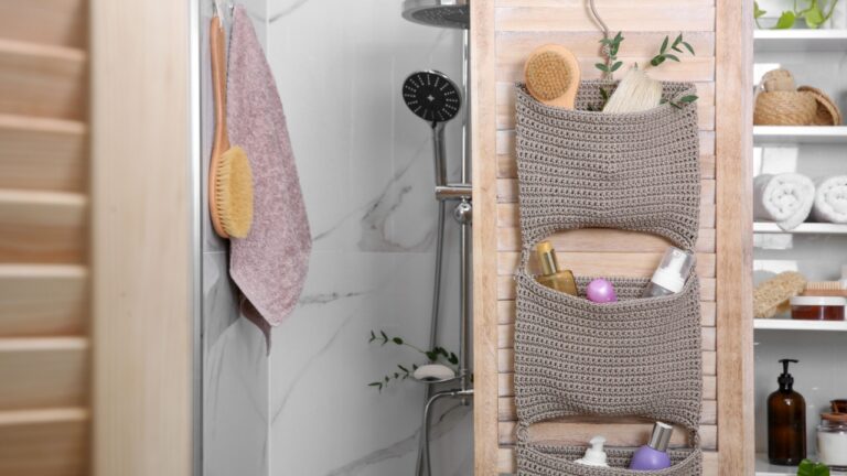 Knitted organizer hanging on wooden door in bathroom