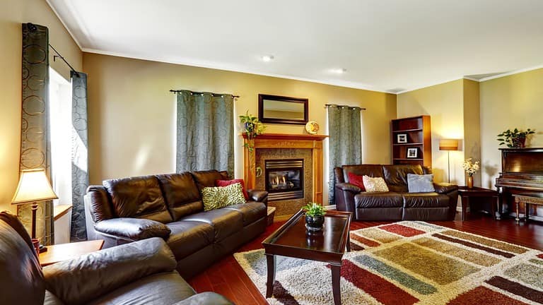 Living room interior with leather couches and colorful soft rug