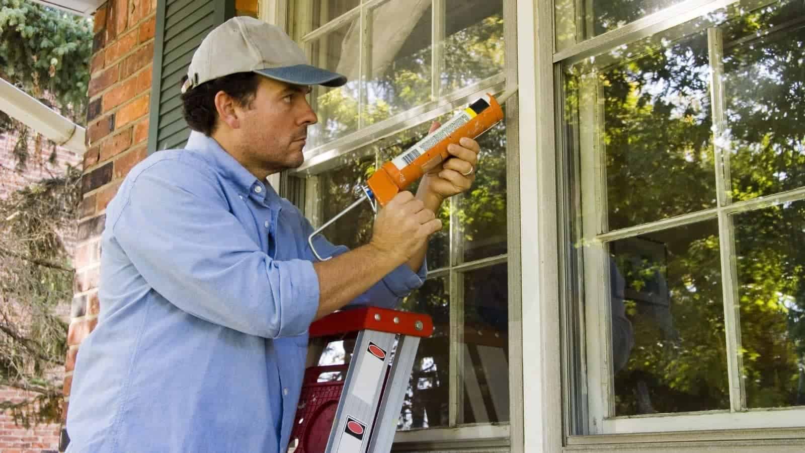 Man sealing window frame with caulk to prevent air leaks
