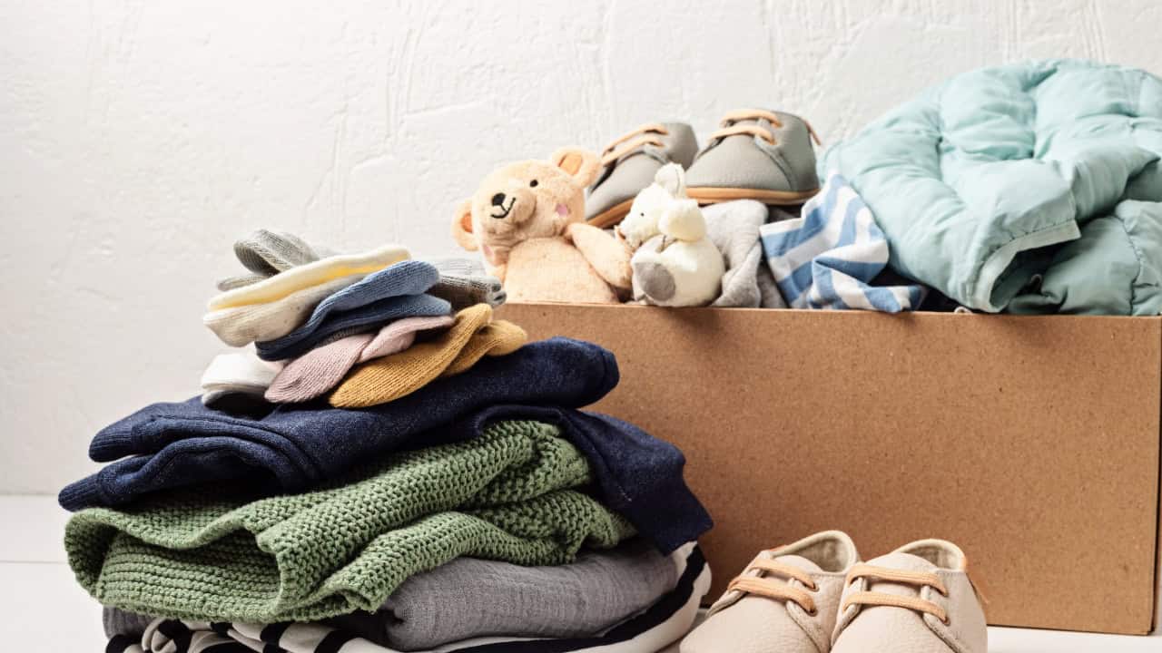 Stack of folded clothing in various colors including green, navy, beige, organized on surface with shoes visible