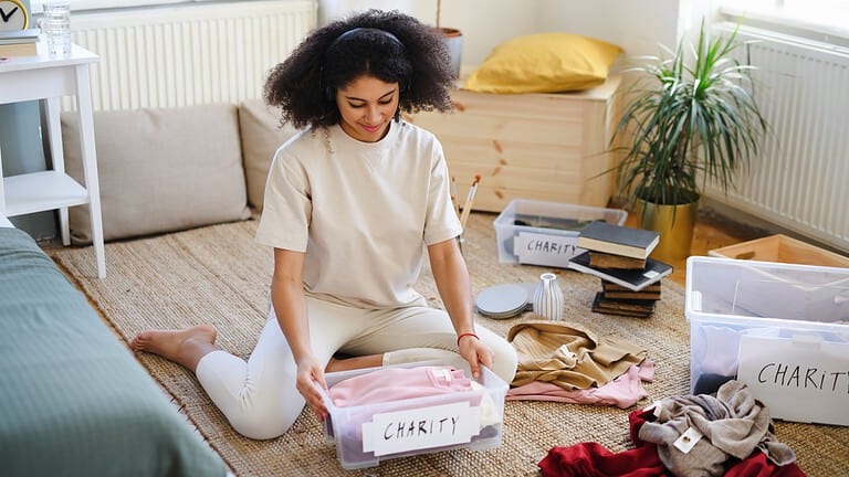 Young woman sorting clothing indoors at home, charity donation concept. marie kondo popping tags, charity giveaway clutter declutter