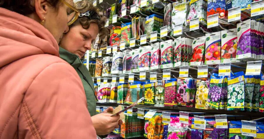 Person in pink shirt shopping at store shelf filled with colorful products, reading product label