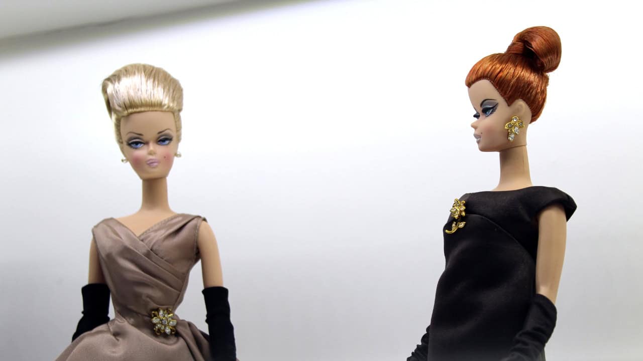 Two vintage-style Barbie dolls dressed in elegant 1950s fashion, posed against a plain background
