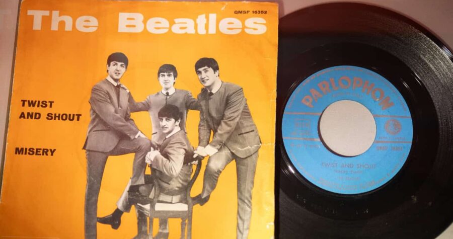 The Beatles vinyl record with orange cover featuring band members, and a black Parlophone record beside it