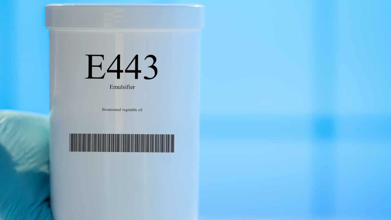 A white container with a label reading "E443" and "Emulsifier," featuring a barcode, clean background with a blue tone, the container is tightly closed, indicating it contains a food additive or chemical substance