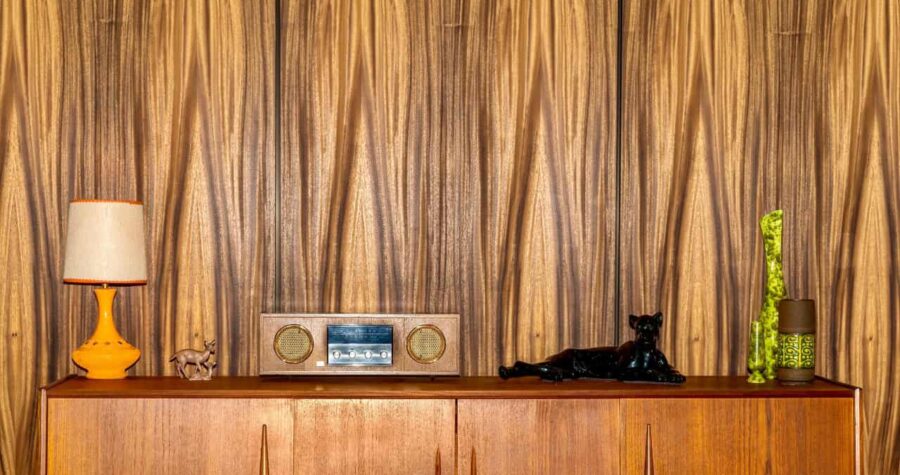 Vintage wood-paneled wall, mid-century modern decor, retro wooden cabinet, old-fashioned radio, black panther figurine, warm-toned interior design