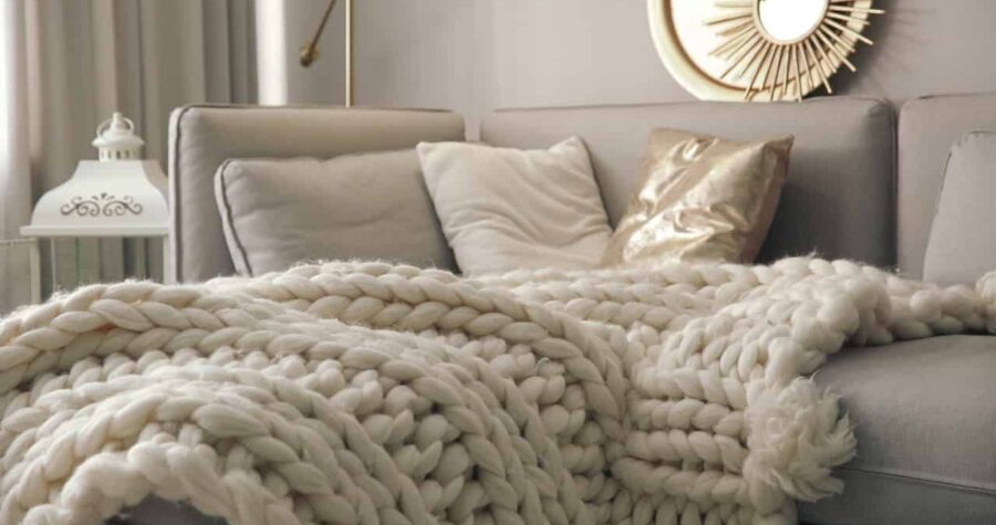 Cozy living space, chunky knit blanket, soft neutral pillows, modern home decor, warm and inviting atmosphere