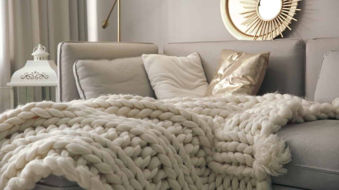 Cozy living space, chunky knit blanket, soft neutral pillows, modern home decor, warm and inviting atmosphere