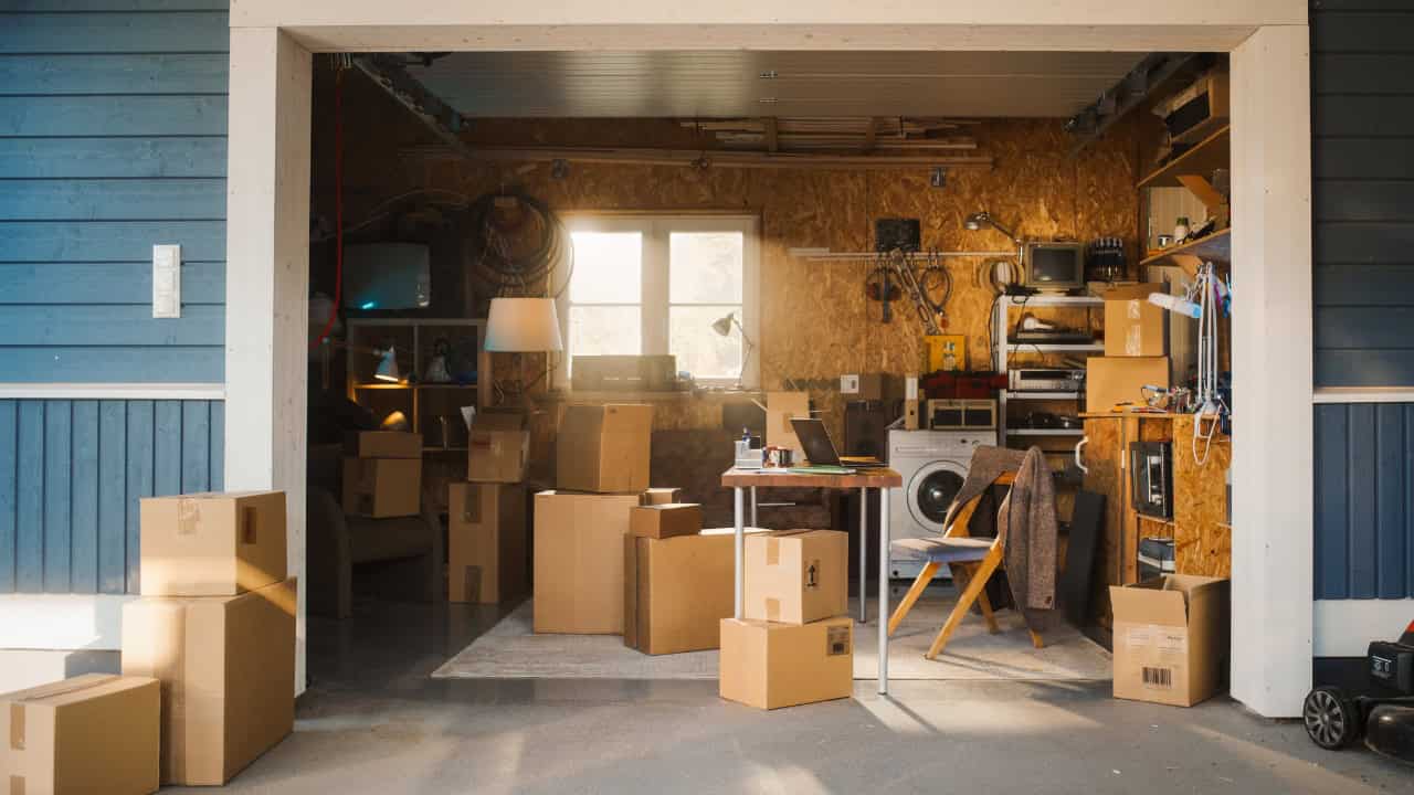 Dusty basement or storage room with cardboard boxes, wooden shelves, concrete floor, small window with natural light
