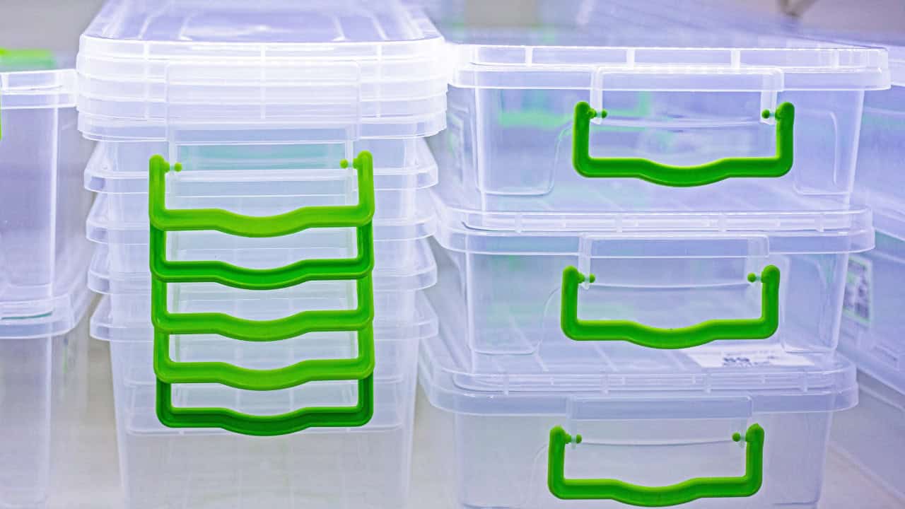 Stacked transparent storage boxes with green handles, organized containers with visible lids, close-up of plastic bins for storage, neatly arranged storage bins with color-coded handles