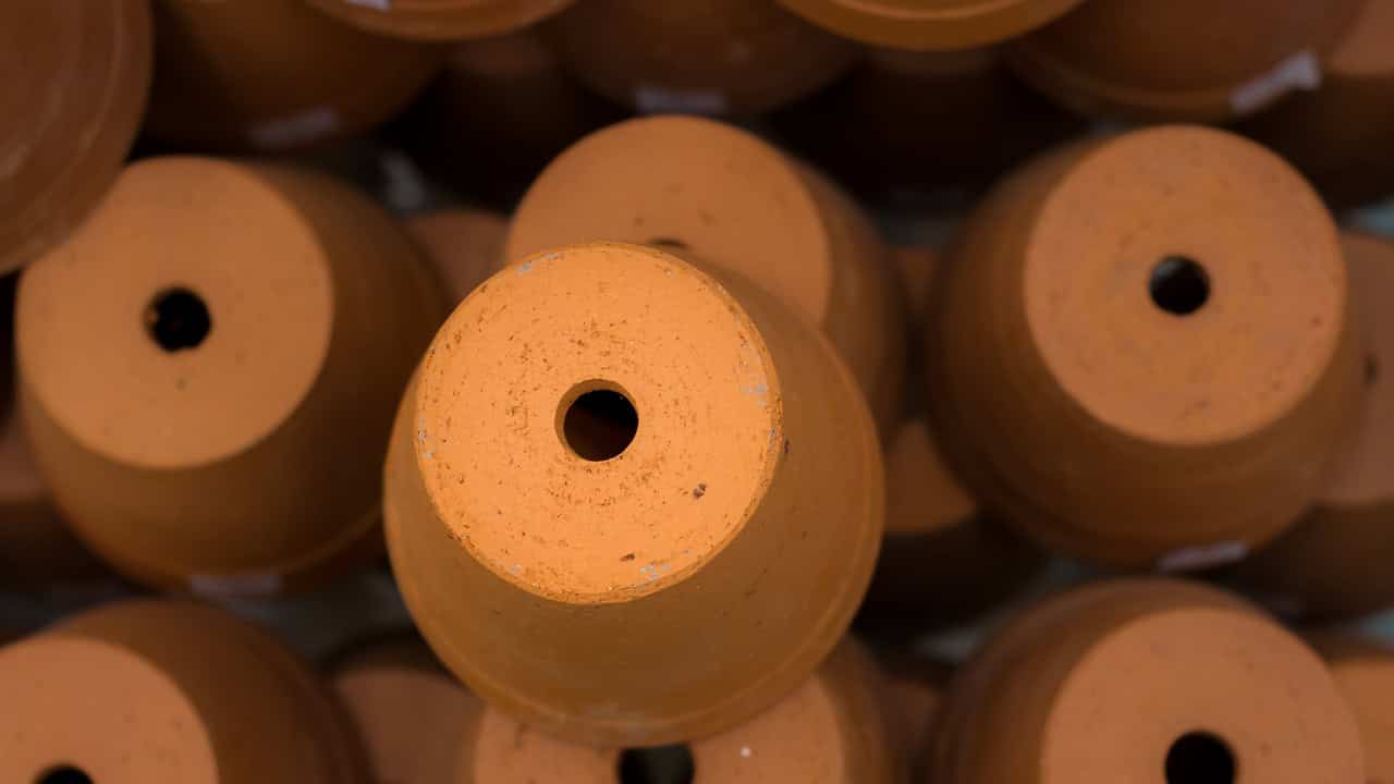 Stacked terracotta flower pots viewed from the top, each with a central drainage hole, arranged closely in a pile