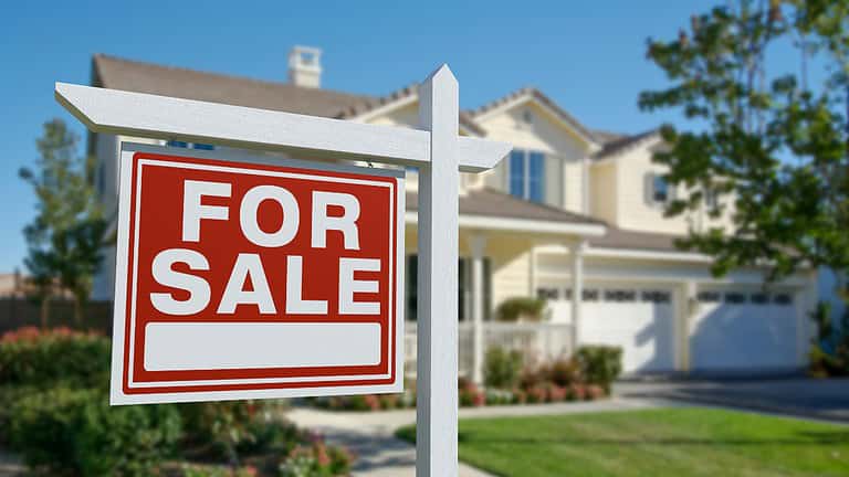 Red and white "For Sale" sign in front of a modern two-story suburban house