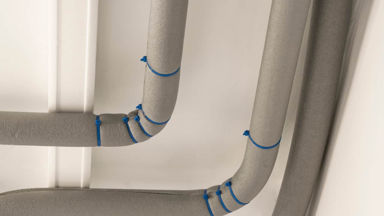 Insulated pipes with foam covers secured with blue ties, used for temperature protection