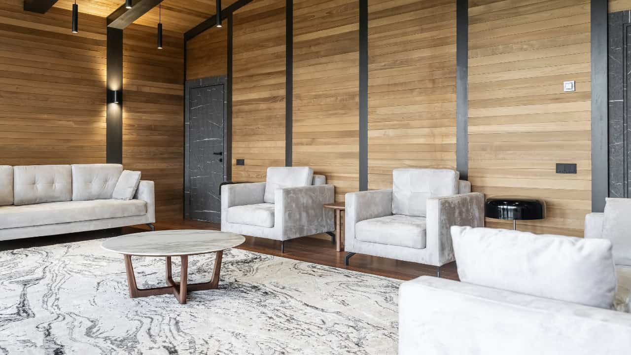 Modern living room with wooden walls, two gray armchairs, round coffee table, neutral rug, simple and minimalist decor, contemporary interior design