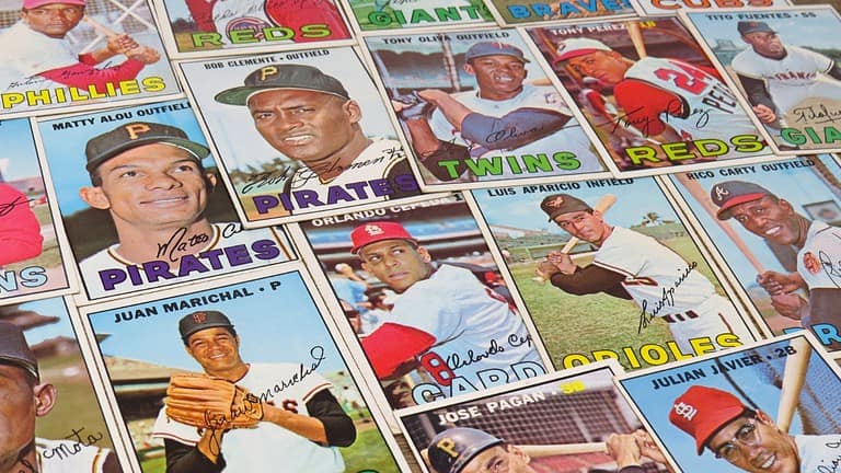 A collection of vintage baseball cards from various teams, featuring players like Roberto Clemente, Juan Marichal, and Matty Alou, with colorful team names and player signatures on each card