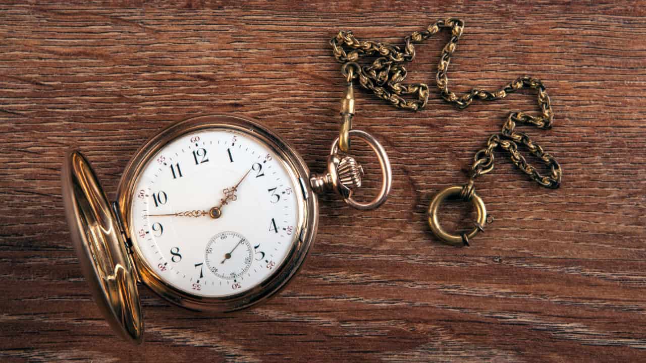 Vintage pocket watch with chain and keys on wooden surface showing antique timepiece