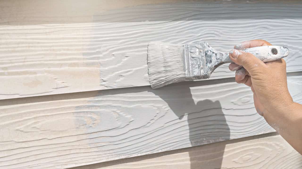 Person painting house exterior with roller