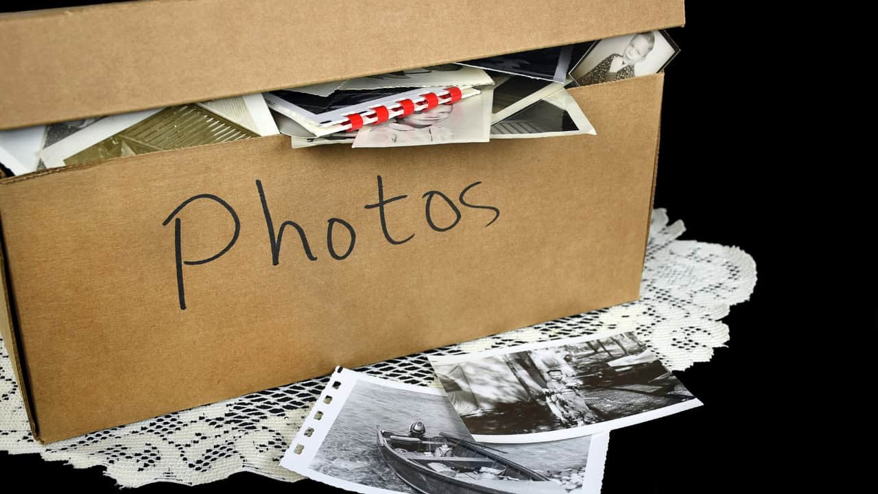 Cardboard box labeled "Photos," filled with old photographs, black-and-white images spilling out, nostalgic memories, vintage photography collection