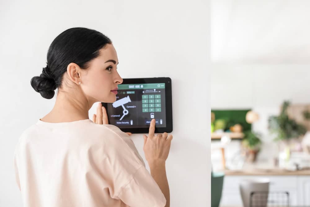 A person using a smart home security system, controlling a device on a smart home control panel, adjusting settings, interacting with technology, managing smart home features