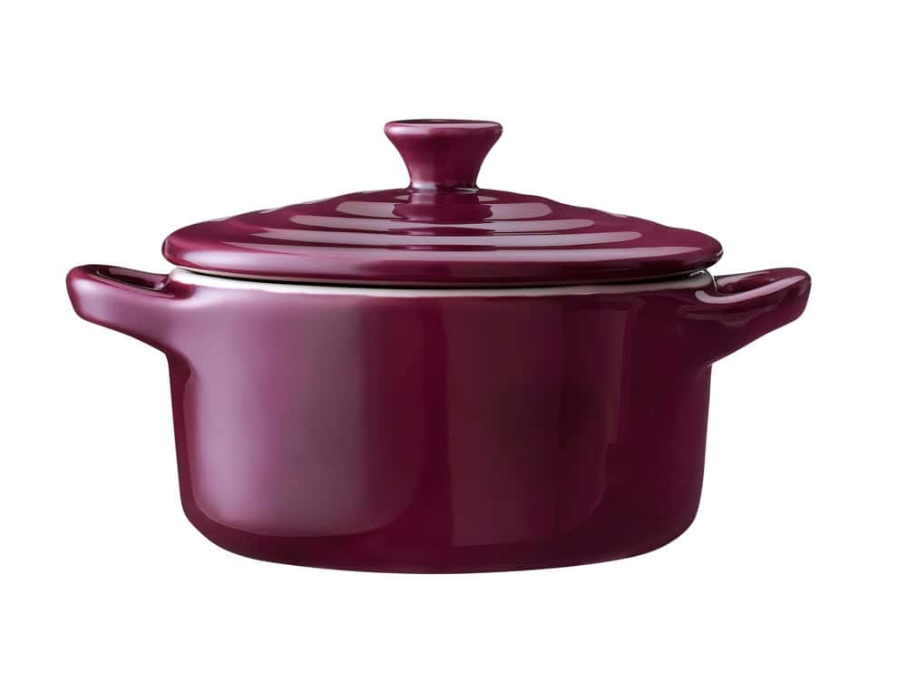 Glossy deep purple ceramic casserole dish with lid and side handles, isolated on a white background