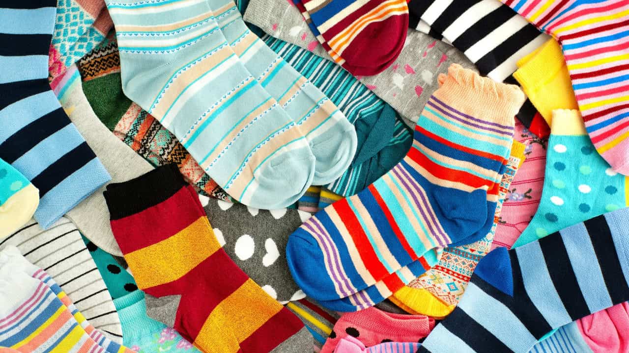 Colorful striped socks, various patterns and colors, neatly arranged socks in a pile, a mix of bright, vibrant, and fun designs, pairs of socks with different styles