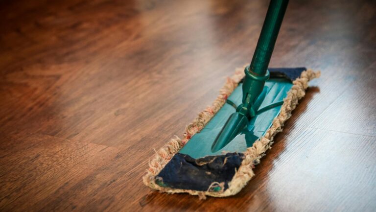 A detailed view of a mop cleaning a wooden floor, showing texture and pattern.