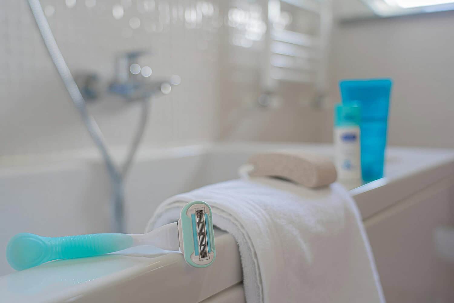 A focused shot of a razor on a towel beside a bath, evoking a clean and fresh bathroom setting.