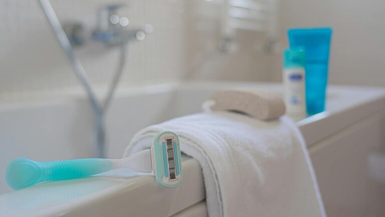 A focused shot of a razor on a towel beside a bath, evoking a clean and fresh bathroom setting.