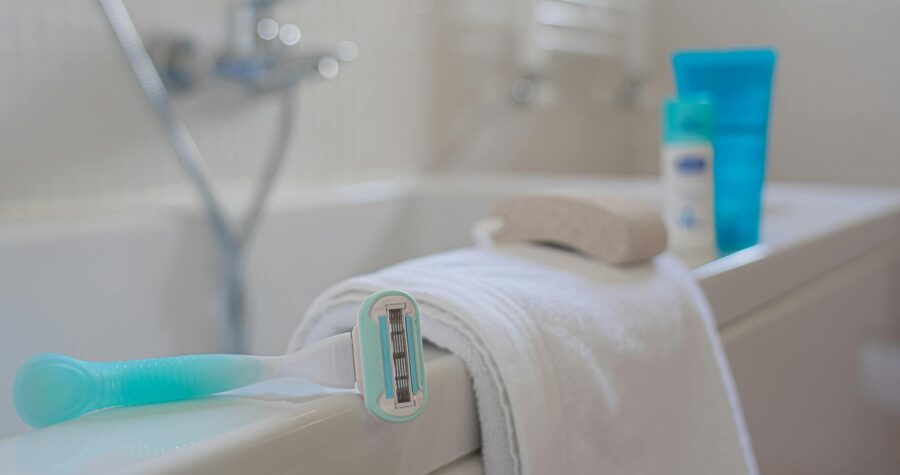 A focused shot of a razor on a towel beside a bath, evoking a clean and fresh bathroom setting.