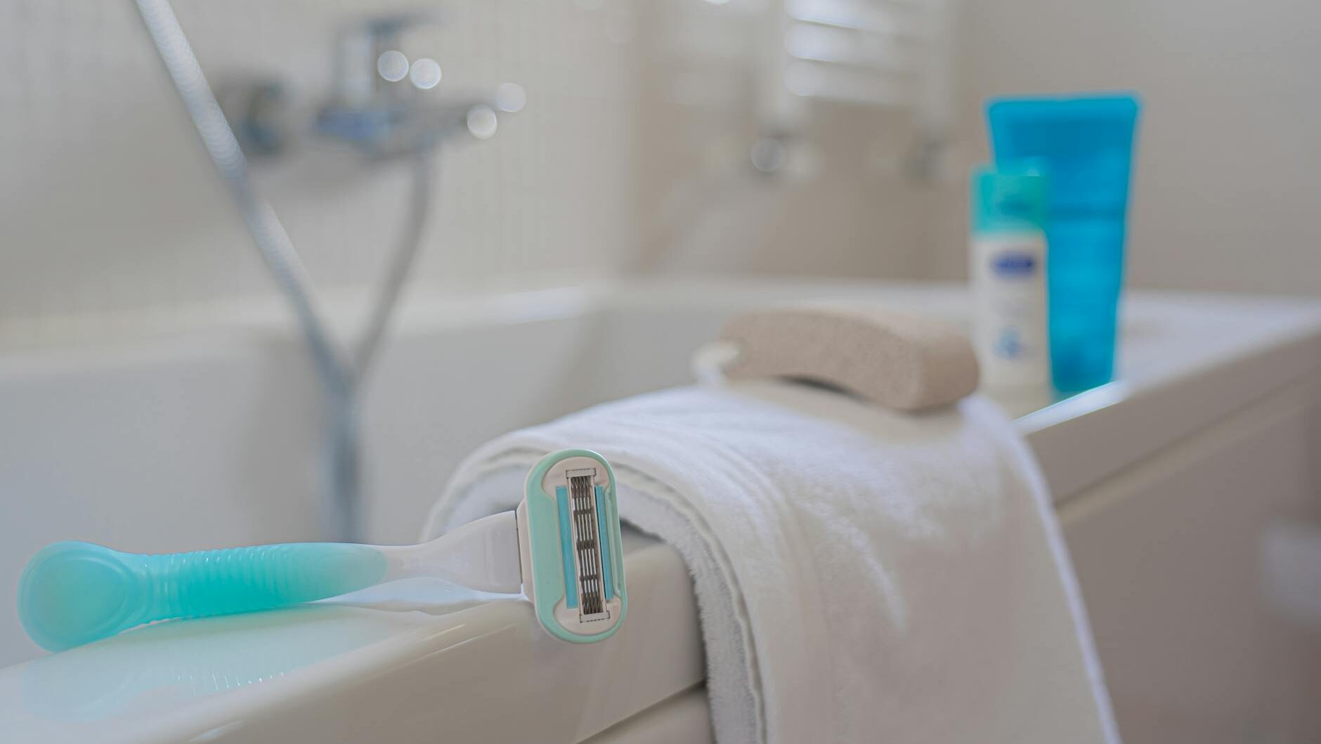 A focused shot of a razor on a towel beside a bath, evoking a clean and fresh bathroom setting.