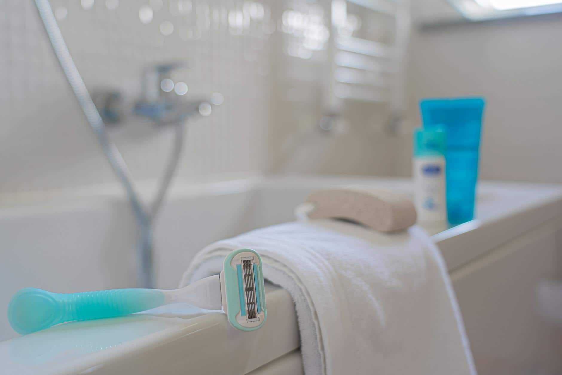 A focused shot of a razor on a towel beside a bath, evoking a clean and fresh bathroom setting.