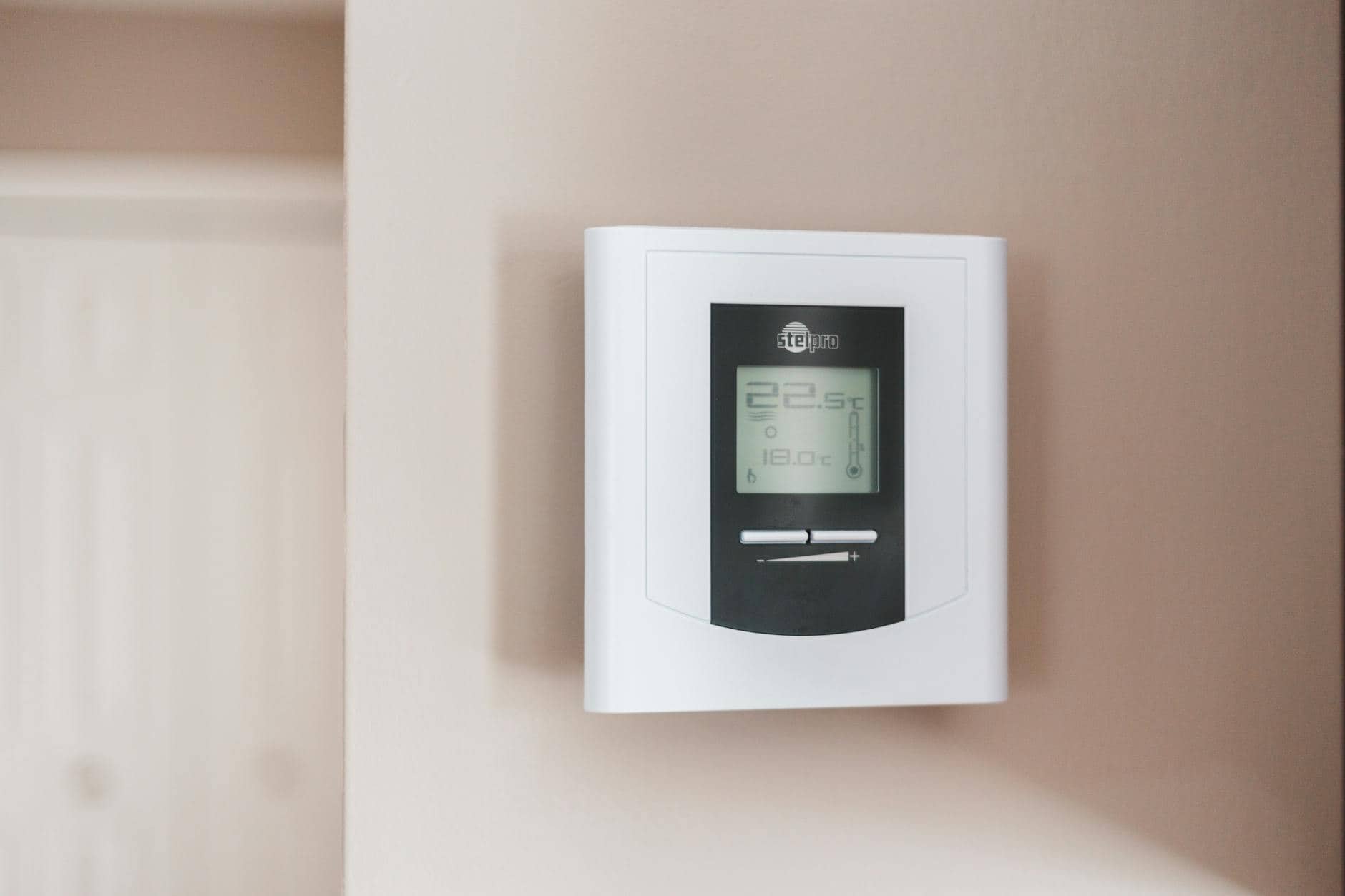 Close-up of a modern digital thermostat mounted on a wall, displaying temperature settings in Celsius
