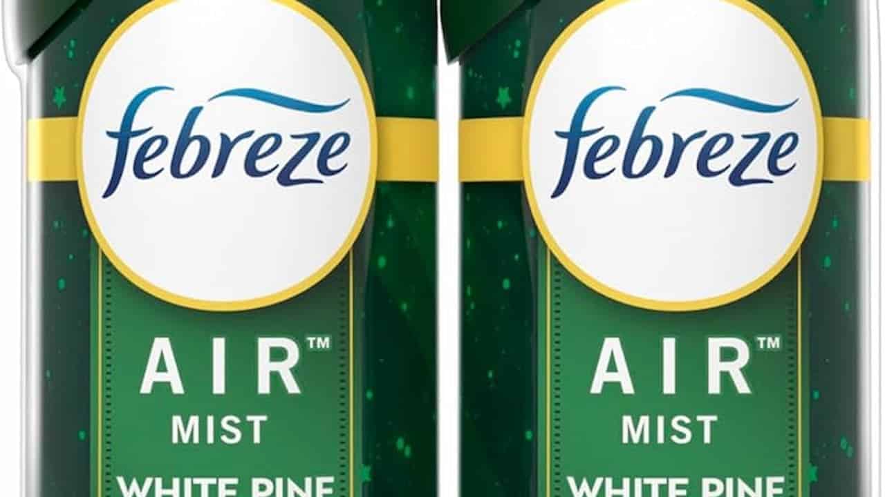 Two Febreze Air Mist cans, White Pine scent, dark green packaging with a festive design, yellow bands, and the Febreze logo in blue on a white circular background