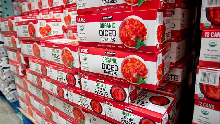 Stacked boxes of organic diced tomatoes and organic tomato paste, labeled with "Kirkland" brand, packaging close-up, grocery store display, food product, canned tomatoes, pantry item