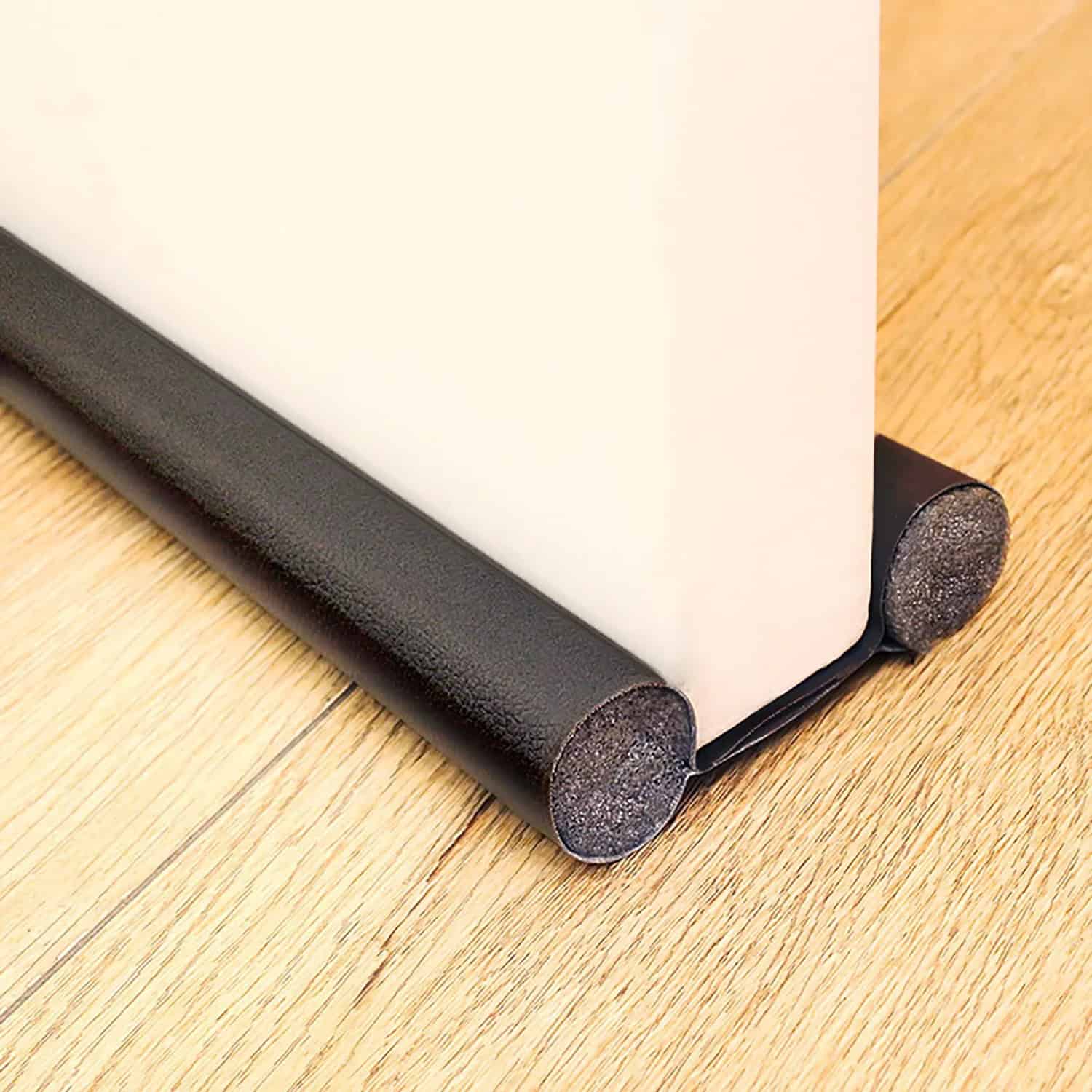 Door draft stopper, black rubber material, placed at the bottom of a door, sealing the gap between the door and the floor, designed to block drafts