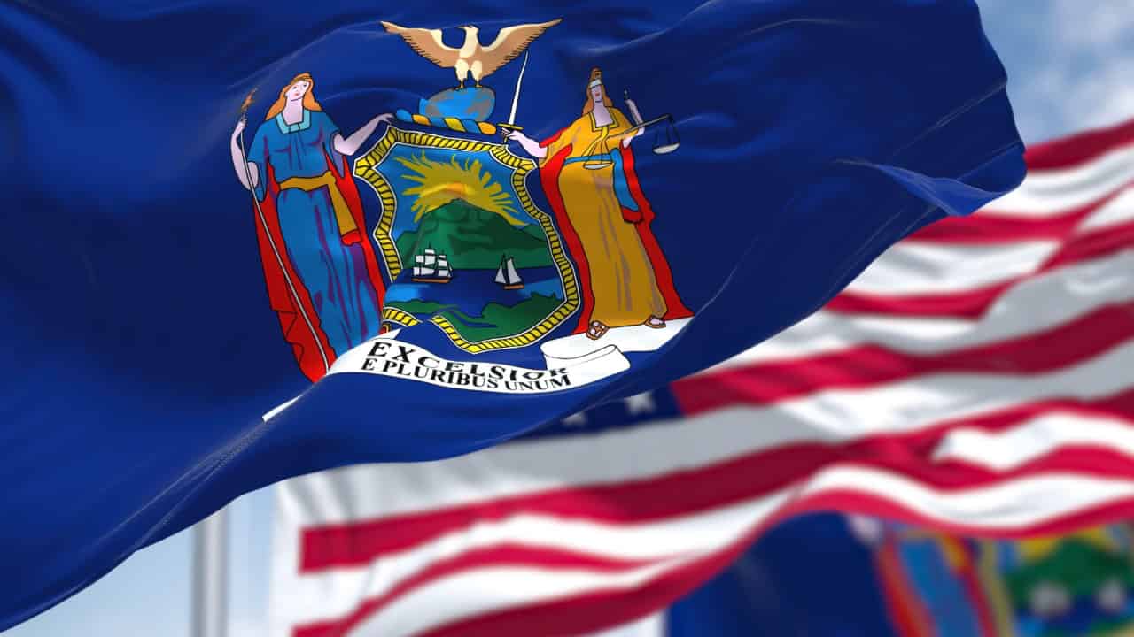 New York state flag waving in wind with urban skyline