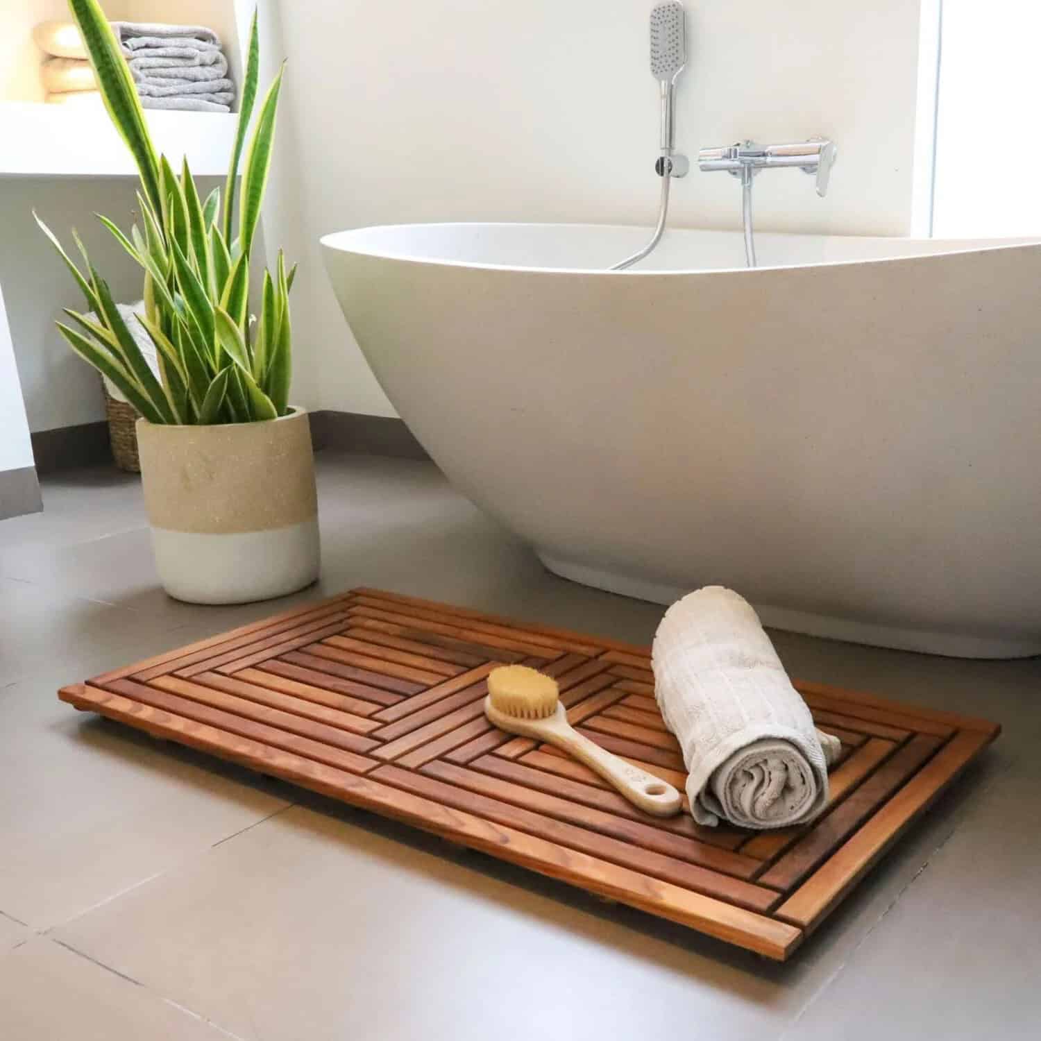 Wooden bathmat, A minimalist bathroom with a freestanding white bathtub, wooden bath mat, aloe vera plant in a pot, towel and bath brush placed neatly on the mat
