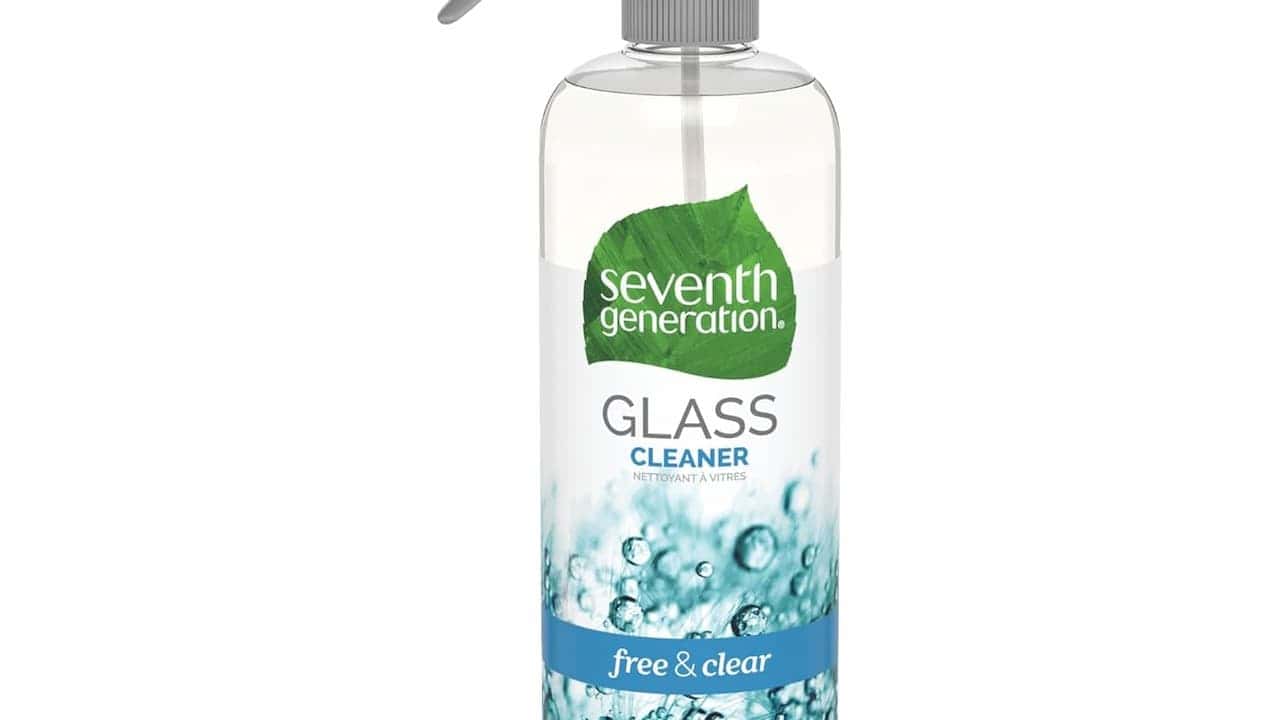 A clear spray bottle of Seventh Generation Glass Cleaner, featuring a green leaf logo, gray spray trigger, and blue water droplet imagery at the bottom
