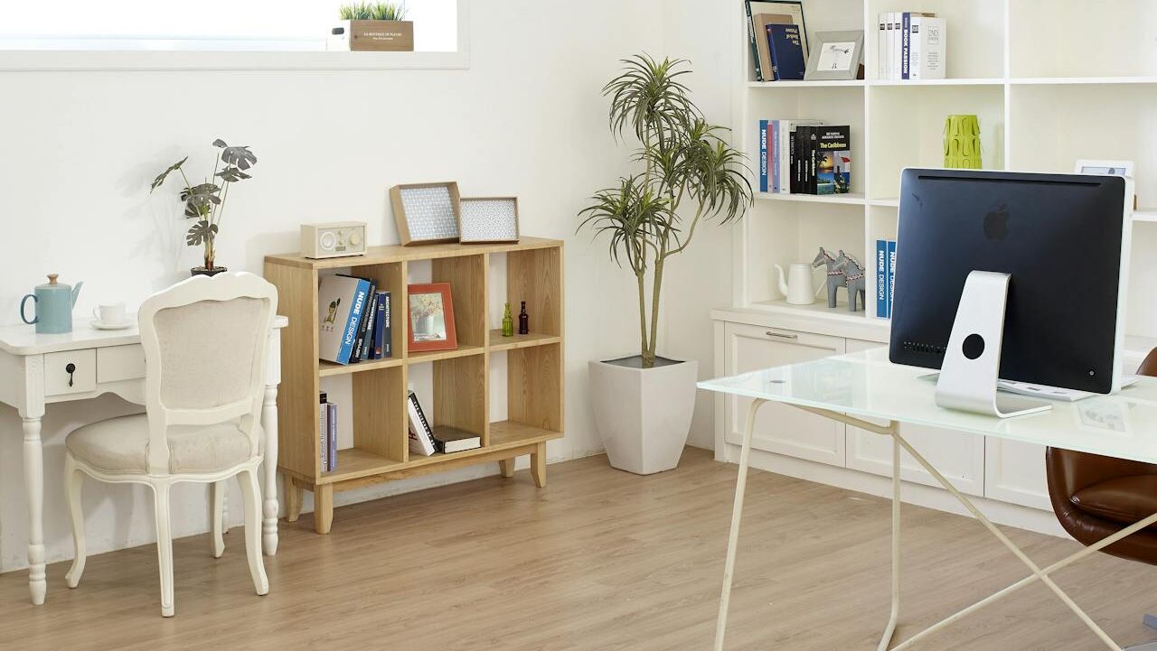 Modern home office, bright and well-lit space, white walls with minimalist decor, wooden flooring, large white bookshelves filled with books and decorations, elegant white writing desk with a vintage chair, organized and stylish workspace