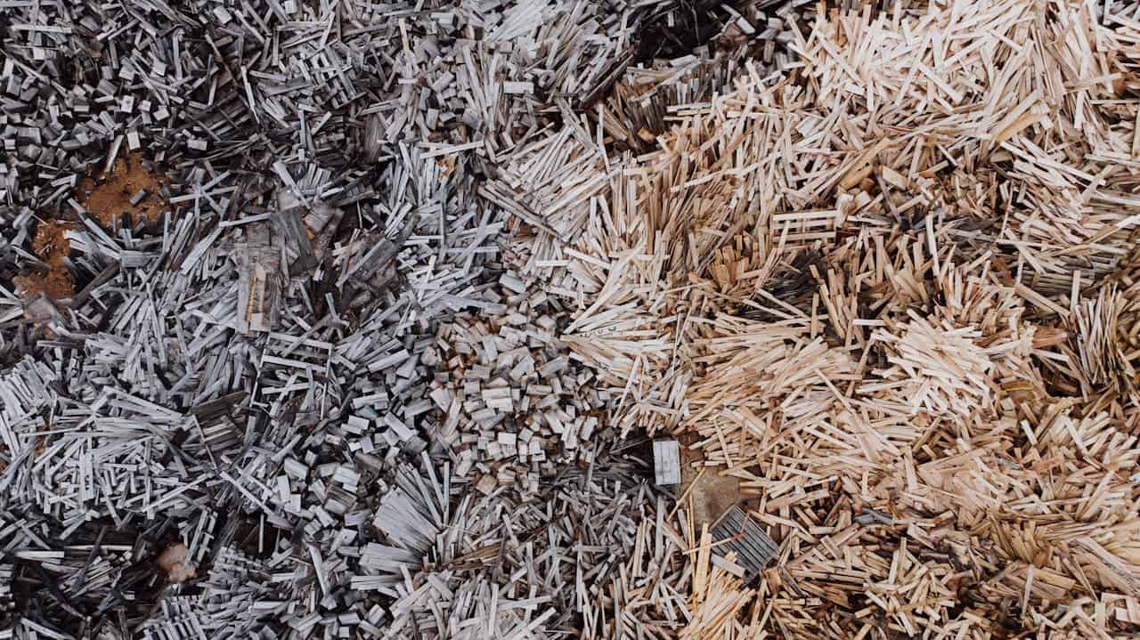 Mixed wood chippings, light and dark shredded wood, rough texture, natural mulch material, scattered wooden fragments, biodegradable organic matter, used for gardening and landscaping