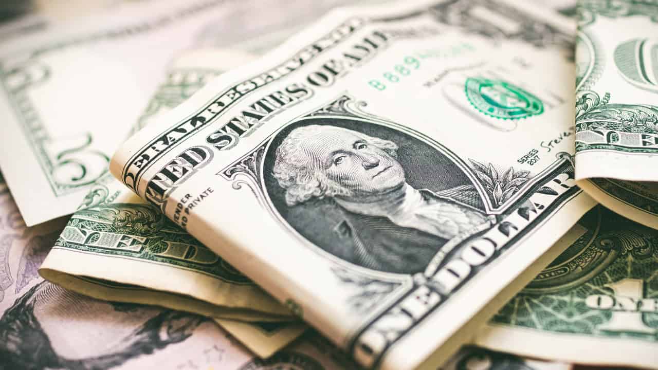 U.S. dollar bills, with a prominent one-dollar bill featuring George Washington's portrait, stacked together, symbolizing currency or money