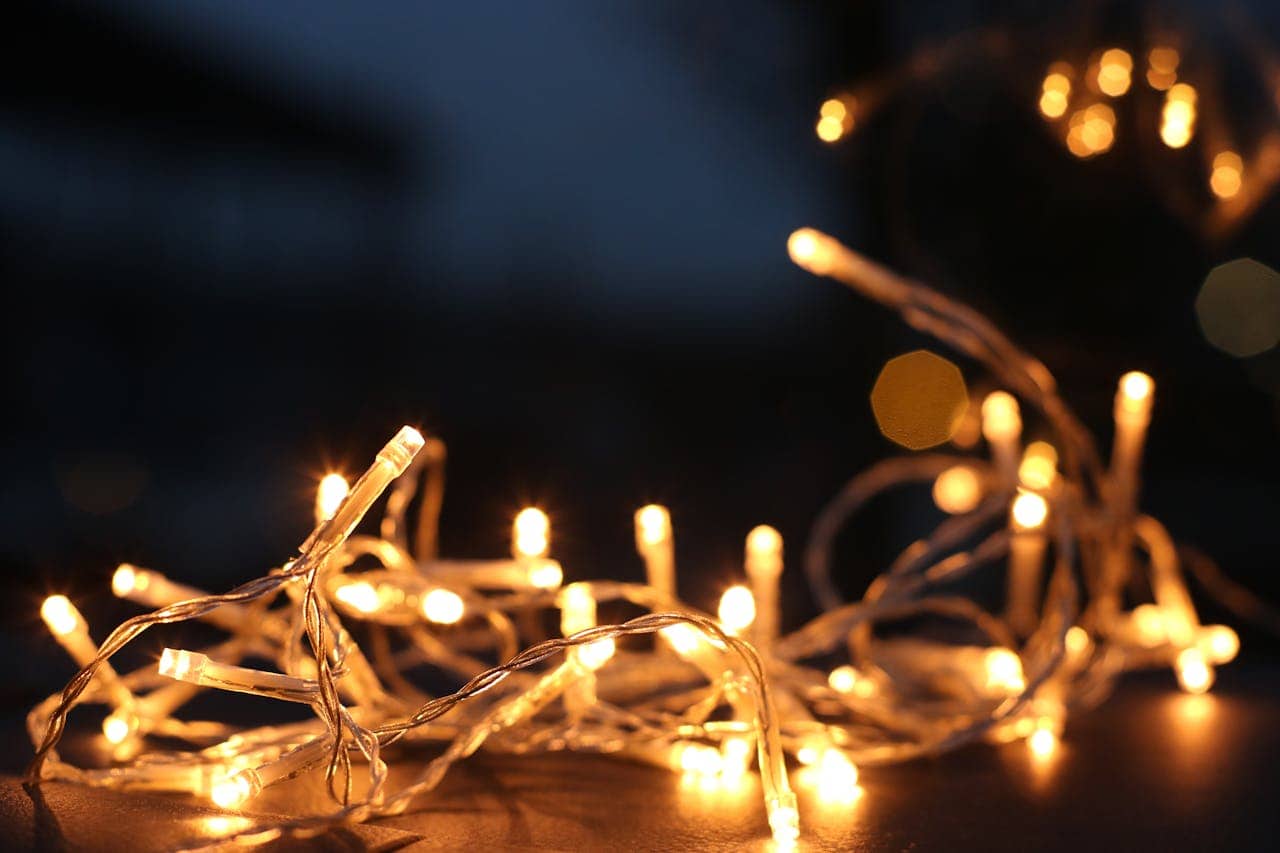 A close-up image of glowing white string lights tangled on a surface, creating a warm, cozy atmosphere with blurred background bokeh