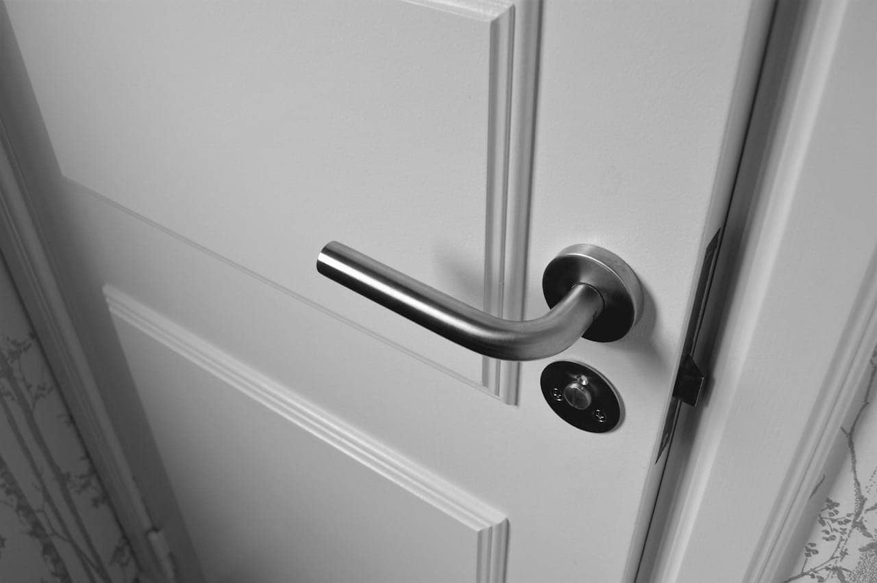 Door handle with modern metallic finish, circular keyhole, white door background